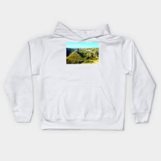 Rocky canyon partly covered with green grass and randomly placed shrubs near Matera Kids Hoodie